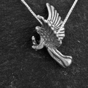 May include: A silver angel pendant with wings outstretched, hanging from a silver chain.