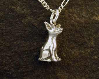Puede incluir: Un collar de plata con un dije de chihuahua sentado detallado. La cadena es de estilo figaro en plata.