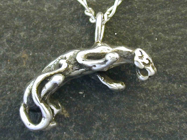 Pu&ograve; includere: Una collana con un ciondolo in argento che presenta una scultura tridimensionale dettagliata di una pantera che salta.