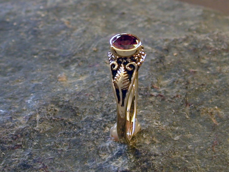 May include: A gold ring with a purple gemstone set in a delicate floral design.