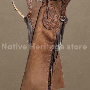 May include: Brown leather chaps with intricate floral tooling and fringe detailing. The chaps feature a decorative yoke and leg panels, with a silver-tone ring. The text "Native Heritage store" is visible.