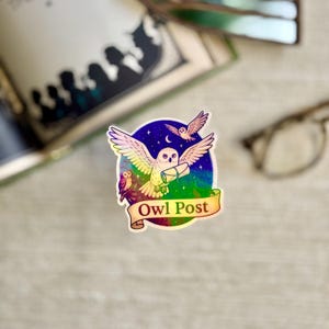 May include: A colorful sticker featuring an owl with outstretched wings carrying a scroll, set against a starry night sky. The sticker has a rainbow gradient and the words "Owl Post" on a banner. A small owl is perched on a branch.
