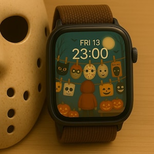 Puede incluir: Reloj inteligente negro con una correa marrón, que muestra un tema de Halloween. La pantalla muestra un fondo verde con máscaras espeluznantes, calabazas y el texto "FRI 13 23:00". Una máscara beige con agujeros para los ojos y la boca está en el fondo.