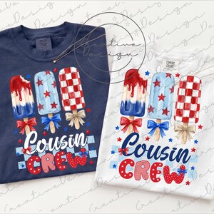 May include: Two t-shirts, one navy blue and one white, each featuring a popsicle design in red, white, and blue. The text "Cousin Crew" is displayed below the popsicles, with red and blue stars and bows.