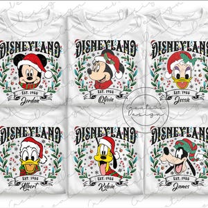 以下が含まれることがあります： 白いTシャツには、サンタ帽をかぶったさまざまなディズニーキャラクターが描かれたディズニーランドのデザインが施されています。各シャツには、キャラクターの名前と「EST. 1955」がキャラクターの画像の下に印刷されています。デザインには、ミッキー、ミニー、ドナルド、プルート、グーフィーが含まれています。