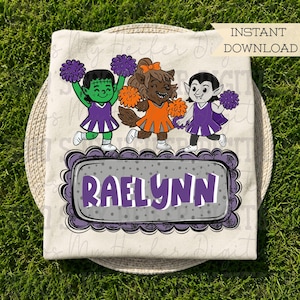 May include: A cream-colored t-shirt featuring a graphic of three monster cheerleaders in purple and orange uniforms with pom-poms. Below them is a gray rectangular frame with a scalloped purple border containing the name RAELYNN in purple text.