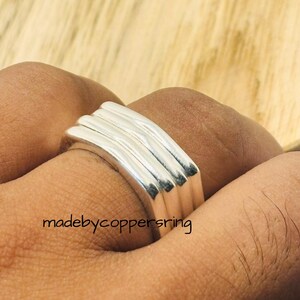 May include: A silver ring with a stacked, ridged design. The ring has a polished finish and is worn on a finger. The text "madebycoppersring" is visible on the image.