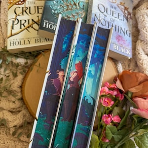 May include: A stack of fantasy novels with colorful covers, including "The Cruel Prince" and "The Queen of Nothing." The spines feature illustrations of characters in a forest setting. A gold crown and flowers are in the background.