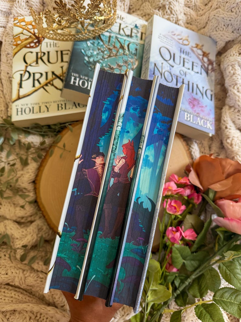May include: A stack of fantasy novels with colorful covers, including "The Cruel Prince" and "The Queen of Nothing." The spines feature illustrations of characters in a forest setting. A gold crown and flowers are in the background.
