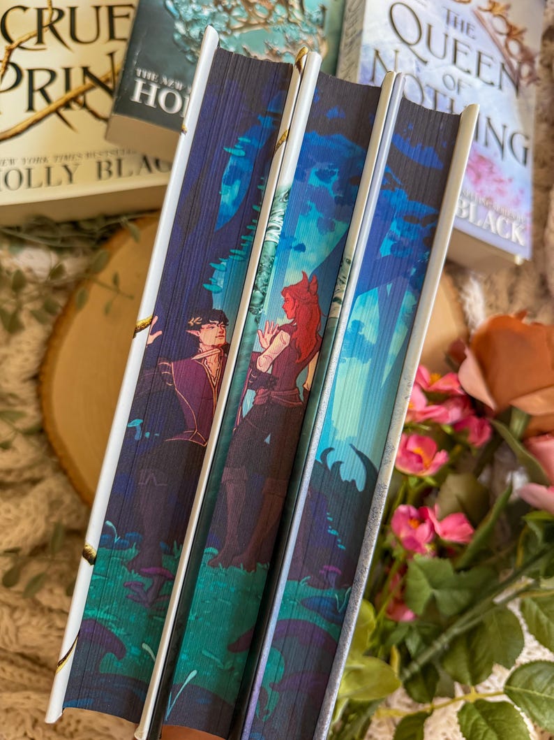 May include: Close-up of three hardcover books with illustrated spines. The spines feature fantasy art with figures in a forest setting, in shades of blue, purple, and green. The book titles are partially visible.