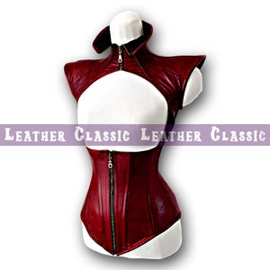 May include: A burgundy leather corset and bolero set displayed on a mannequin. The corset has a front zipper and a fitted silhouette. The bolero features a high collar and shoulder accents. The text "LEATHER CLASSIC" is printed across the image.