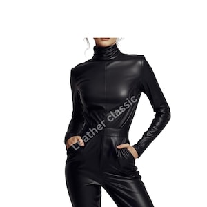 May include: A black leather jumpsuit with a turtleneck collar and long sleeves. The jumpsuit has a fitted silhouette with a high waist and pockets. The text "Leather classic" is visible on the garment.