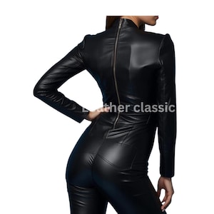 May include: A black leather jumpsuit with a high neckline and long sleeves. The jumpsuit features a full-length zipper down the back and is form-fitting. The text "leather classic" is visible on the image.