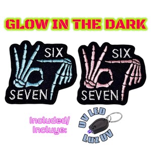 May include: Two black patches with skeleton hand designs, one in blue and one in pink, displaying the numbers "SIX" and "SEVEN". The text "GLOW IN THE DARK" is above the patches. A small UV LED keyring is included.