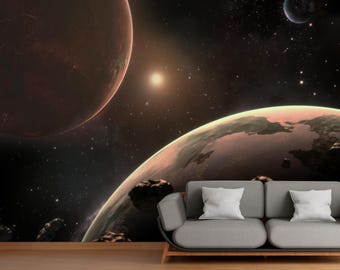 May include: A space-themed wall mural featuring planets, stars, and a bright sun. The mural depicts a cosmic scene with a large, reddish-brown planet and a smaller, green and brown planet. A gray sofa with white pillows is in front of the mural.
