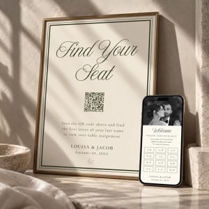 May include: A framed wedding seating chart sign with a cream background and dark border, featuring the text Find Your Seat, a QR code, and the names Louisa & Jacob. A smartphone displays a matching digital interface with a couple's photo.