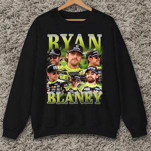 May include: Black crewneck sweatshirt featuring a collage of images of Ryan Blaney, with the name "RYAN BLANEY" in large, neon green letters. The images show Blaney in a racing uniform and hat.