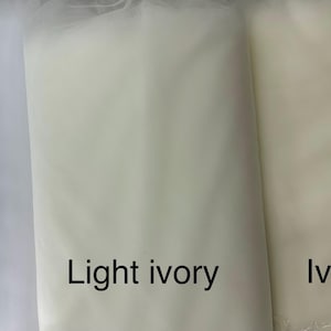 May include: Three fabric samples in white, light ivory, and ivory. The white fabric is on the left, followed by light ivory and ivory on the right. The names of the colors are written below each fabric sample.