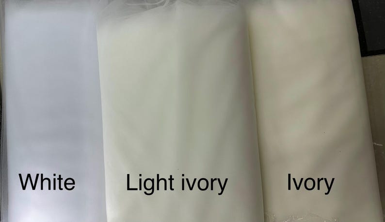 May include: Three fabric samples in white, light ivory, and ivory. The white fabric is on the left, followed by light ivory and ivory on the right. The names of the colors are written below each fabric sample.