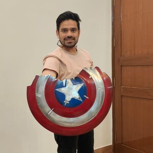 May include: A Captain America shield prop, featuring a red, white, and blue color scheme. The shield has a star in the center and a silver metallic rim. The shield is approximately 24 inches in diameter.