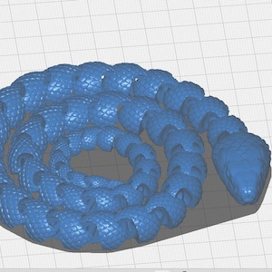 Op de afbeelding: Een opgerold blauw slangmodel met een getextureerd, geschubd oppervlak. De kop van de slang is zichtbaar en het lichaam is in een cirkelvormig patroon gekruld. Het model staat op een rasterachtergrond, met een blauwe "Slice"-knop rechtsonder.