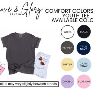 May include: A dark gray youth tee shirt with rolled sleeves, paired with light blue denim shorts and pink sneakers. The image also displays a color chart with options like white, black, pepper, and true navy. Text reads "Grove & Glory Studio".