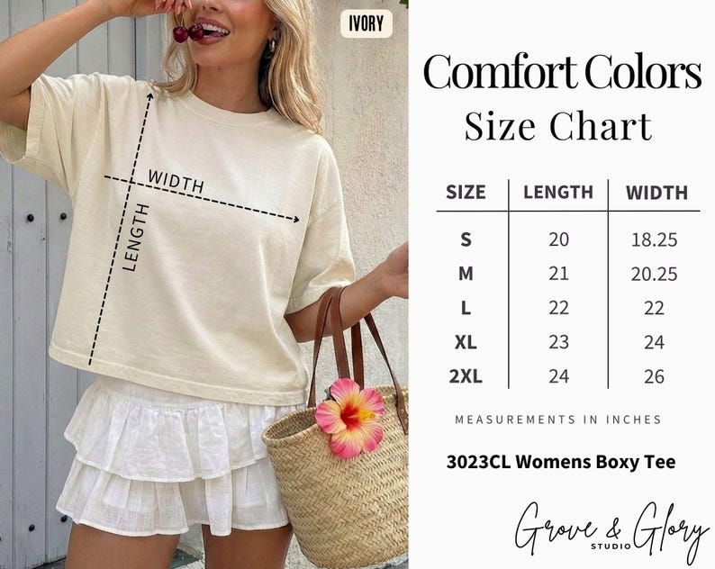 May include: A woman wearing an ivory-colored boxy tee shirt and white skirt, holding a straw tote bag with a pink flower. The image includes a size chart with measurements in inches for the tee shirt, ranging from S to 2XL.