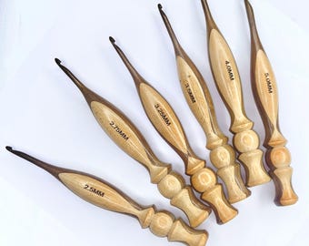 May include: Six wooden crochet hooks with varying sizes, from 2.5MM to 5.0MM, are arranged diagonally. Each hook features a light-colored wood handle with a darker wood accent and the size printed on the handle.
