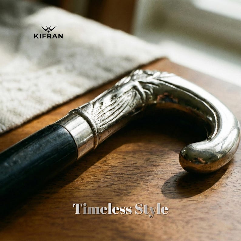 May include: A close-up of a walking cane with a silver-colored handle and a black shaft. The handle has a decorative design. The text "Timeless Style" is at the bottom of the image.