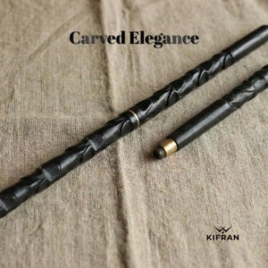 May include: Two black, carved wooden wands with gold-colored accents. The wands have intricate, textured designs and are displayed on a neutral-toned fabric. The text "Carved Elegance" is at the top.