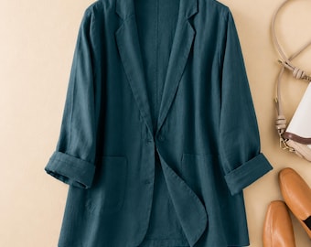 May include: A dark teal blazer featuring a notched lapel, a single-button front closure, and two front patch pockets. The long sleeves are finished with folded cuffs, and the garment is displayed on a wooden hanger against a plain background.