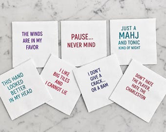 May include: Seven white square paper napkins, each printed with different colorful text: The winds are in my favor, Pause... never mind, Just a Mahj and tonic kind of night, This hand looked better in my head, I like big tiles and I cannot lie, I don't give a crack... or a bam, and Don't hate the player, hate the Charleston.