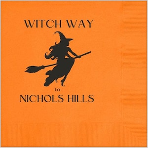 May include: A bright orange square paper napkin featuring a black silhouette of a witch flying on a broomstick. The text printed in black reads WITCH WAY to NICHOLS HILLS, with the witch graphic positioned between the two lines of text.