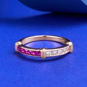 Könnte beinhalten: Ein Ring aus Roségold mit einer Kanalfassung, die einen Farbverlauf aus quadratisch geschliffenen, leuchtend pinken Edelsteinen auf der einen und klaren weißen Edelsteinen auf der anderen Seite zeigt, getrennt durch kleine vertikale Metallstege.