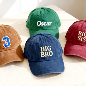 May include: Four baseball caps in brown, green, navy blue, and maroon. The brown cap features a blue and white number 3 patch. The green cap has the white text Oscar. The navy blue cap has the text BIG BRO, and the maroon cap has BIG SIS.