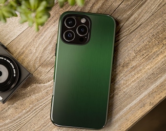 May include: A dark green phone case with a brushed metal texture. The case has a sleek design and covers the back and sides of the phone. The camera lenses are visible. The case is on a wooden surface.