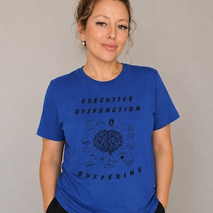 May include: A royal blue short-sleeved t-shirt featuring a black graphic print. The text reads "EXECUTIVE DYSFUNCTION" at the top and "BUFFERING" at the bottom, surrounding a central illustration of a brain with various small icons.