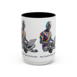 May include: White ceramic mug with a black interior. The design shows a robot wearing headphones and a colourful shirt, working on a laptop. The text "Hey ChatGPT give me the idea" is printed on the mug.