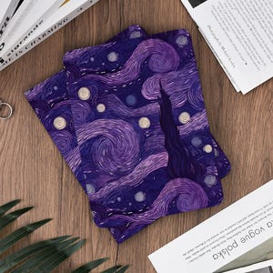 May include: Two purple and blue fabric items with a swirling starry night design, reminiscent of Van Gogh's artwork. The items are placed on a wooden surface, with books and magazines in the background.