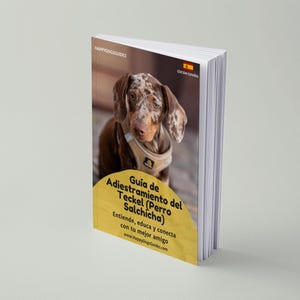 May include: A book titled "Guía de Adiestramiento del Teckel (Perro Salchicha)" features a Dachshund dog on the cover. The book has a yellow banner with text and a Spanish flag icon. The book's title translates to "Training Guide for the Dachshund".