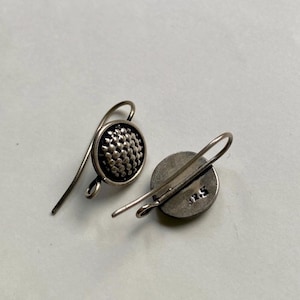 May include: A pair of silver dangle earrings with a textured round disc. The back of one earring has the number 925 stamped on it.