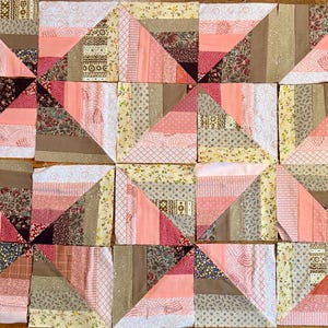 May include: A collection of quilt blocks arranged in a grid pattern. Each block features a triangle design with various fabrics in shades of pink, brown, and cream. The fabrics include floral, striped, and solid patterns, creating a patchwork effect.