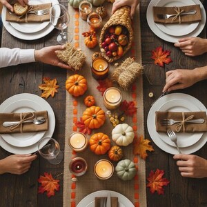 May include: A rustic dining table set for a meal with white plates, brown napkins tied with twine, and silverware. A burlap runner features a cornucopia, small pumpkins, gourds, candles, and scattered autumn leaves, creating a seasonal display.