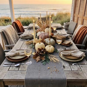 Pode incluir: Uma mesa de jantar de madeira posta para uma refei&ccedil;&atilde;o com ab&oacute;boras brancas e laranja claro, trigo seco e folhas de outono como centro de mesa. A mesa apresenta guardanapos de linho cinza, ta&ccedil;as de vinho, talheres de prata e velas altas. @W4Y.