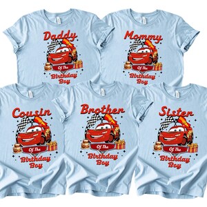 May include: Light blue t-shirts featuring a red race car graphic, a chequered flag, and the text "Daddy", "Mommy", "Cousin", "Brother", and "Sister" above "Of The Birthday Boy".