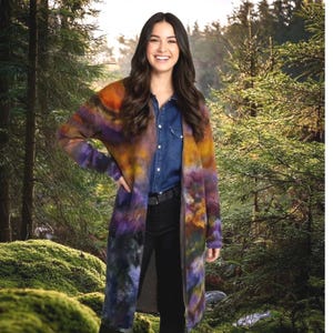 May include: A long-sleeved, open-front cardigan featuring a vibrant, multi-coloured tie-dye pattern in shades of deep purple, burnt orange, and dark charcoal. The garment is worn over a dark blue button-down shirt and black trousers.
