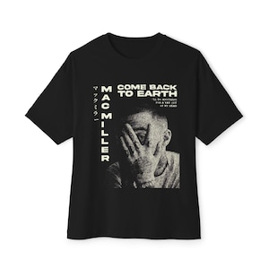 May include: Black t-shirt featuring the text "COME BACK TO EARTH" and "MAC MILLER" with Japanese characters. The design includes a grayscale image of a person covering their face with their hand. The shirt also has the text "I'LL DO ANYTHING FOR A WAY OUT OF MY HEAD."