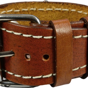 Puede incluir: Primer plano de una correa de reloj de cuero marr&oacute;n con costuras blancas y una hebilla plateada. La correa es gruesa y parece estar hecha de cuero de alta calidad. Las costuras son limpias y uniformes, y la hebilla es brillante.