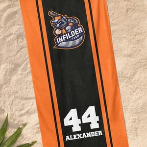 May include: Orange and black beach towel with the text "INFILDER TEAM" and a raccoon graphic. The towel also features the number 44 and the name "ALEXANDER" in white.