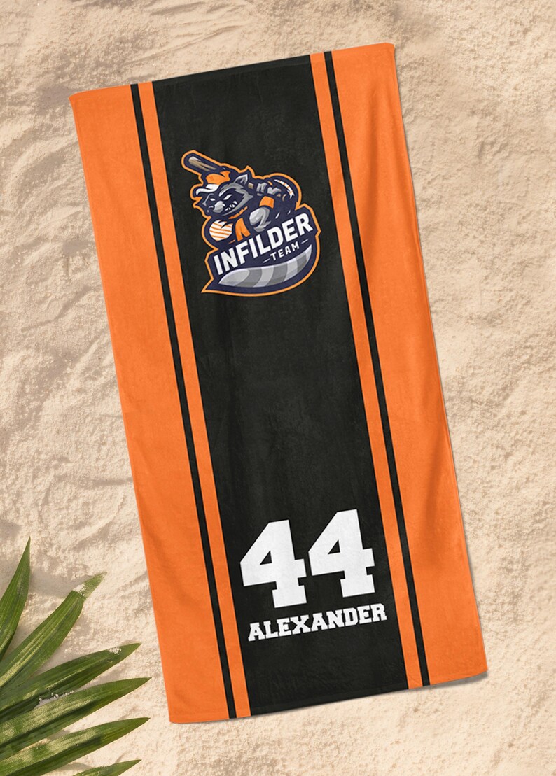 May include: Orange and black beach towel with the text "INFILDER TEAM" and a raccoon graphic. The towel also features the number 44 and the name "ALEXANDER" in white.